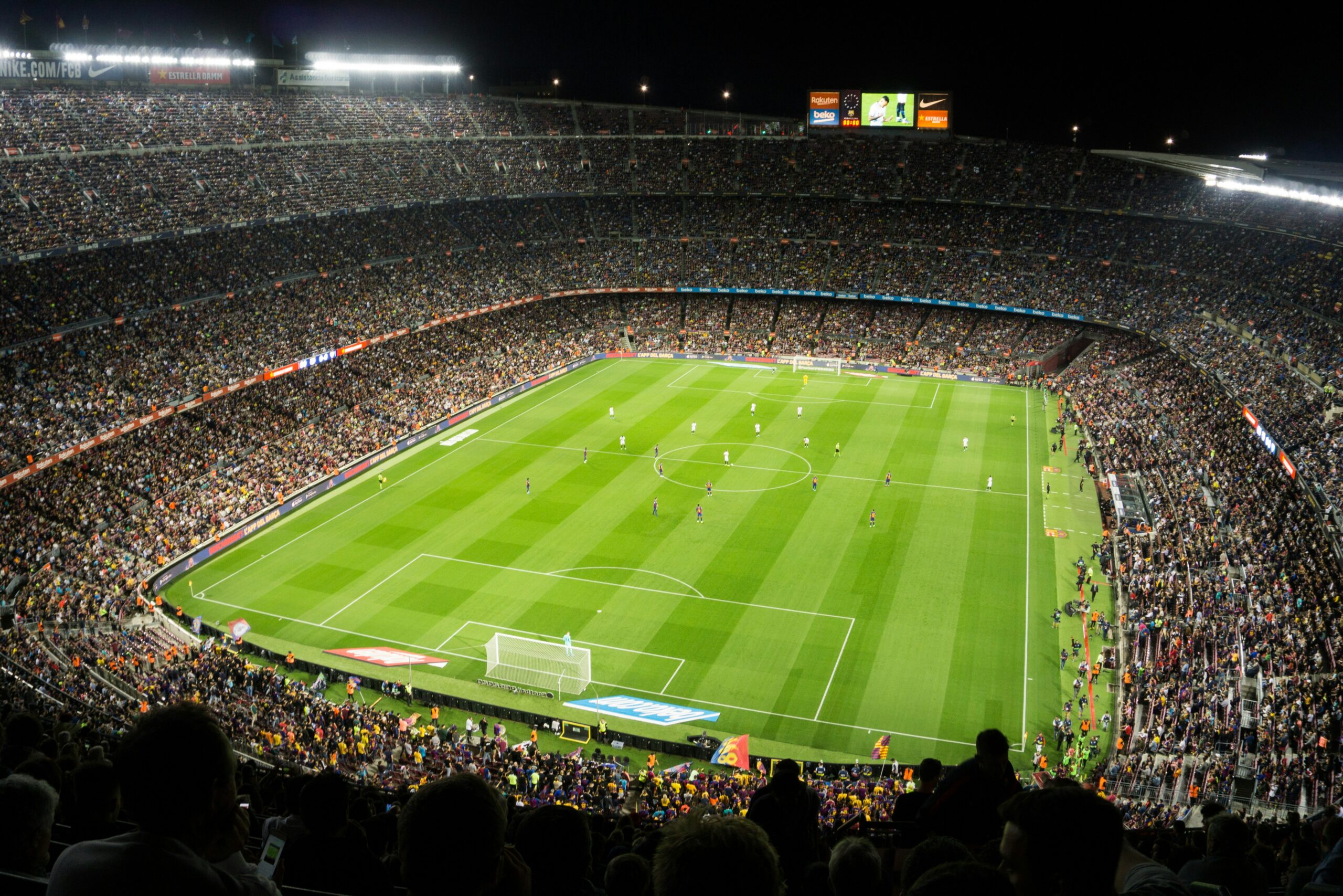 Soccer stadium filled with roaring fans at night with the stadium lights on
